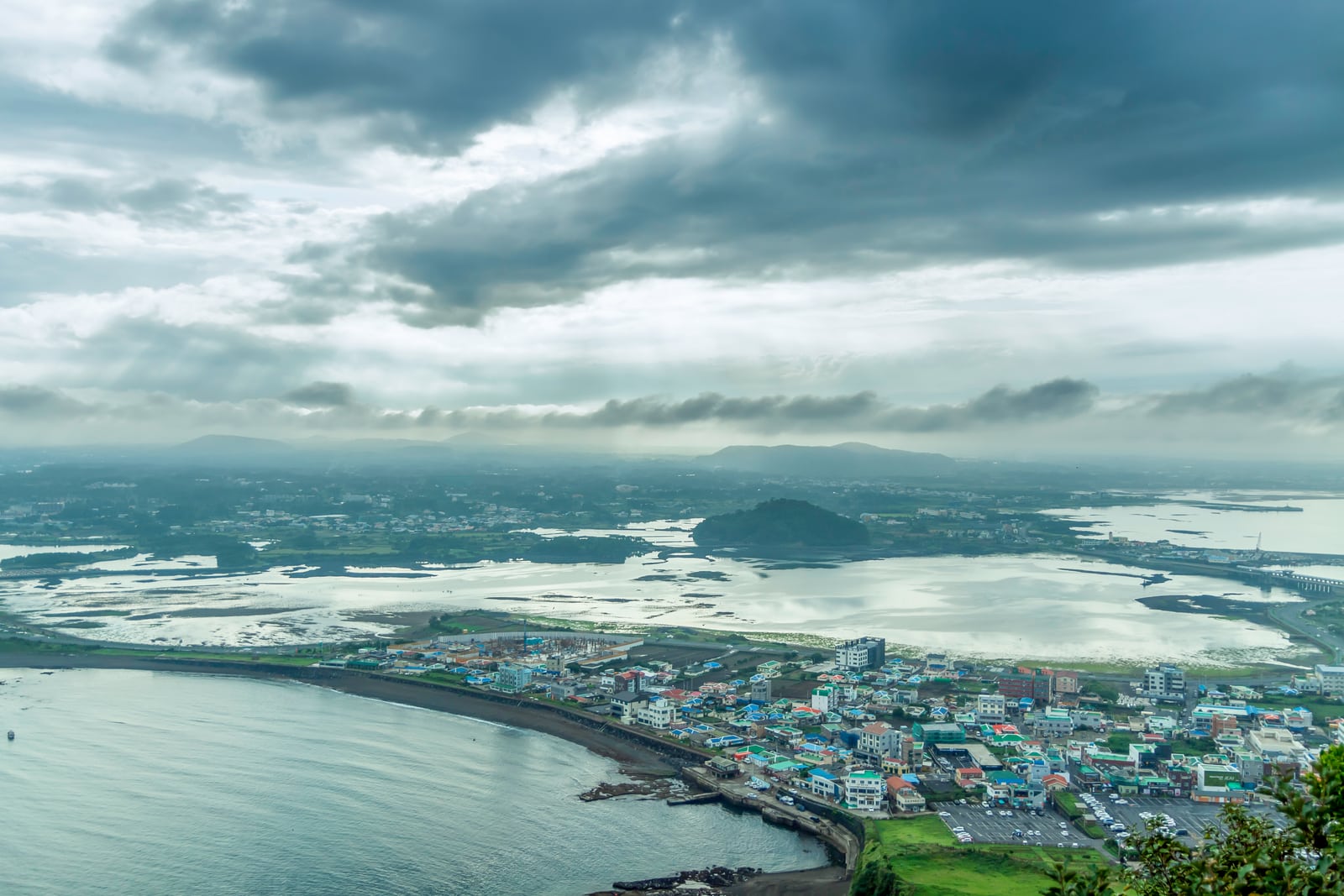 從濟州島城山日出峰俯瞰城山聚落與海岸的實景照片